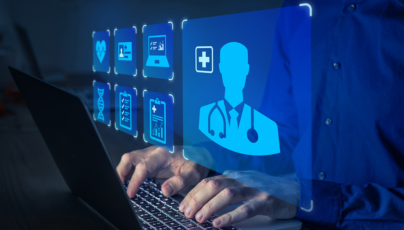 A man works on a computer surrounded by medical imagery