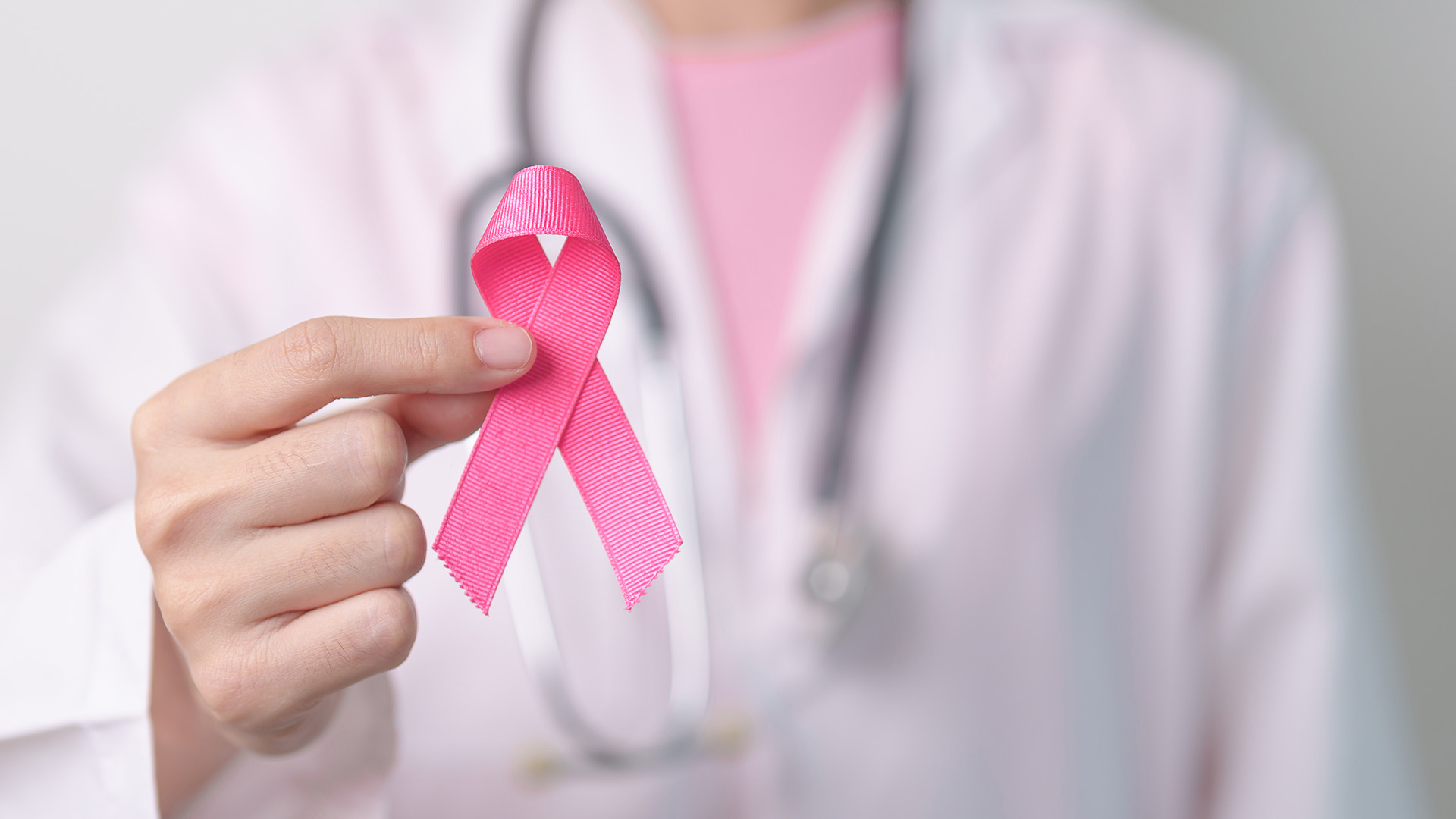 A doctor holds a pink ribbon for October breast cancer awareness month